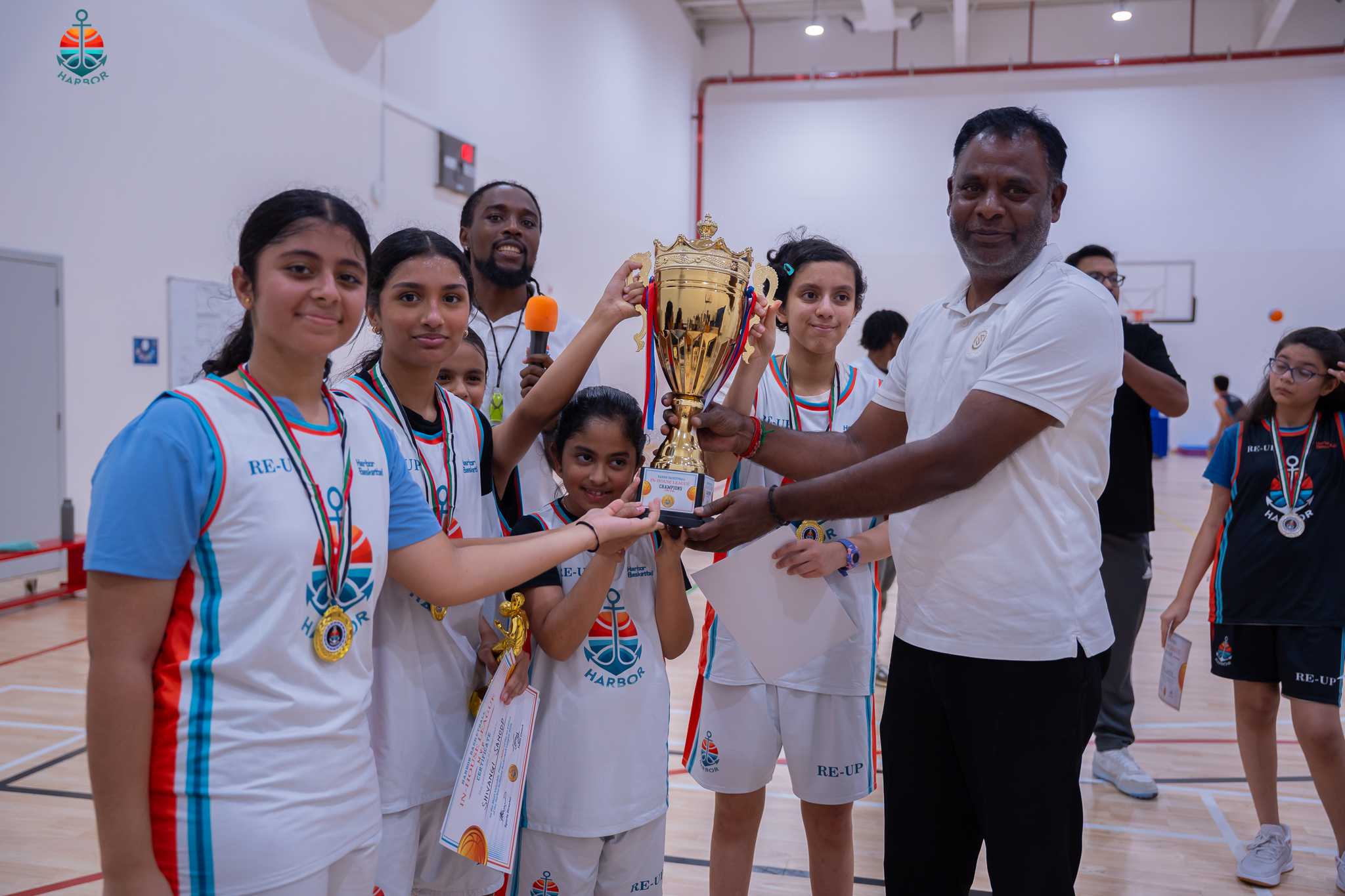 Harbor Sports Academy girls basketball team receiving their trophy from their coach