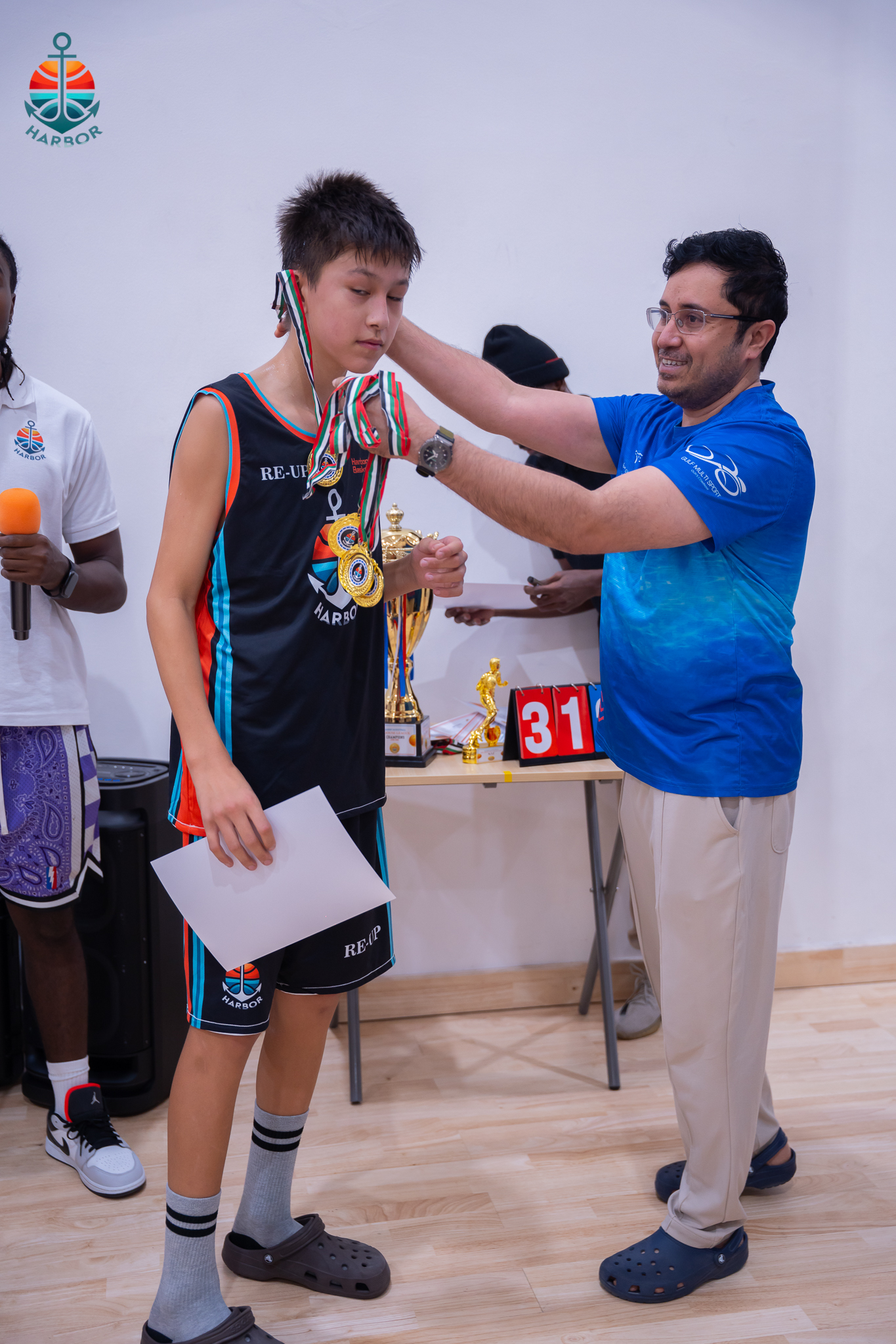 Harbor Sports Academy coach placing a medal around a player neck at the awards ceremony